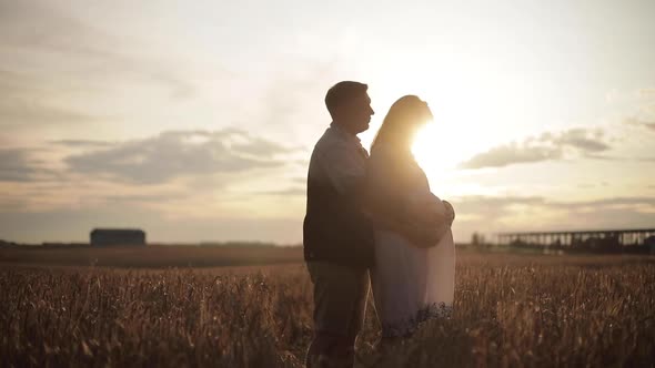 Smiling Husband Tenderly Hugging Pregnant Wife Outdoors