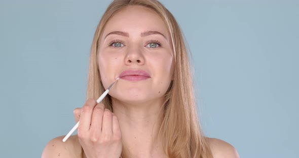 Adorable Blond Woman Apllying Lipgloss Using Cosmetic Brush