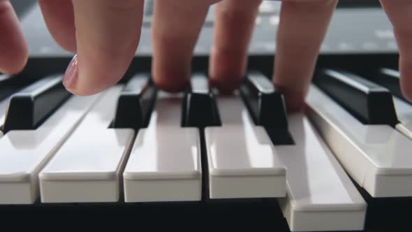 Closeup of the Fingers of a Person with a Pink Manicure Playing an Electronic Synthesizer