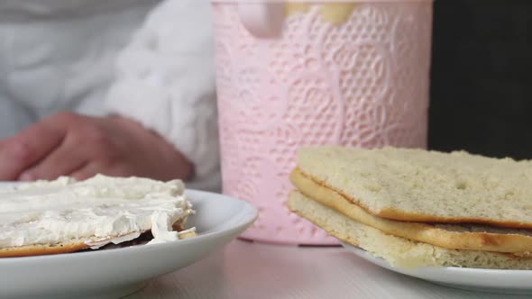 A Woman Puts Cherry Filling On Biscuit Cakes Smeared With Cream.