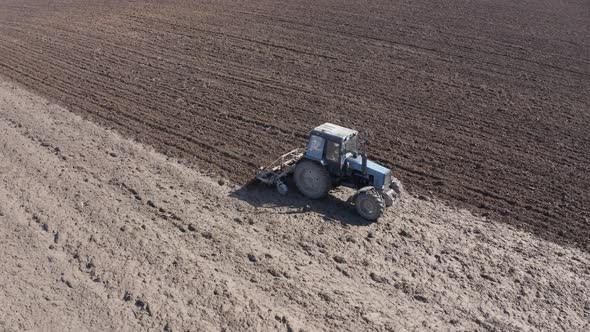 Tractor Plows the Field Before Sowing Seeds on a Spring Sunny Day