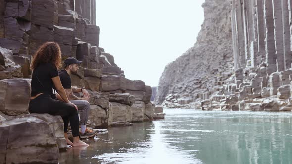 Tourists Sitting by Rocks in the River of Studlagil Canyon, Iceland