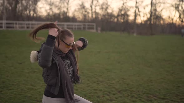 Attractive Young Hipster Woman in a Stylish Look Dancing Freestyle on Urban Background at Sunset or