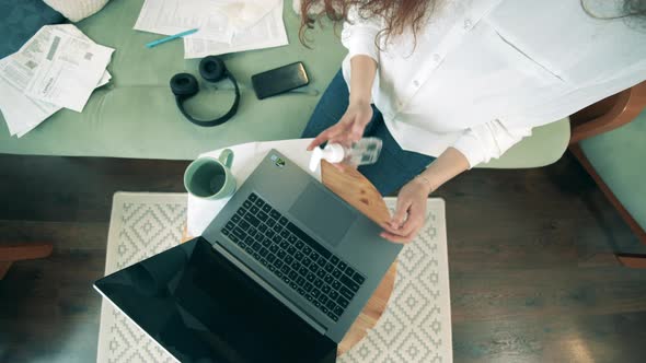 Top View of a Lady Sanitizing Her Hands After Typing on a Laptop