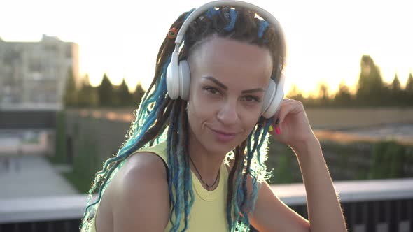 Portrait of Modern Attractive Happy Woman in Headphones on a City Background