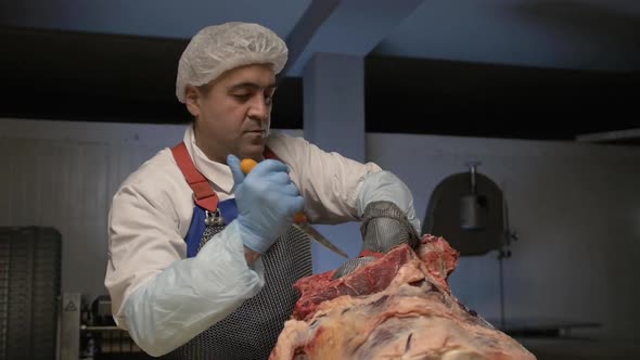 Butcher Cut Raw Meat with Knife at Table in Slaughterhouse