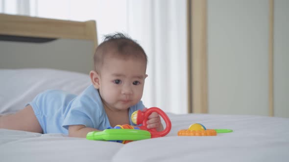 Family concept. The baby is lying alone playing with toys on the bed