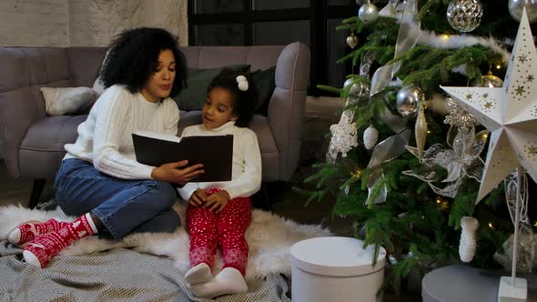 Portrait of a Happy African American Mom Reading a Fairy Tale To Her Little Daughter
