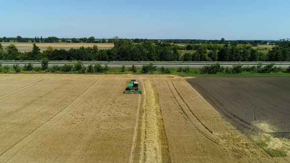 Aerial Drone Footage. Flight Over a Wheat Field with Harvestaer Along the Highway