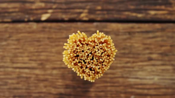 Bunch of spaghetti arranged in heart shape on a wooden table