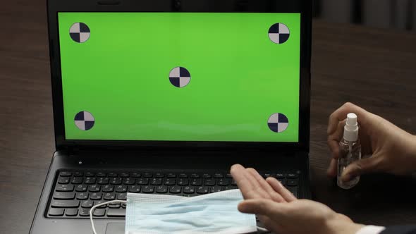 Man's Hand Takes Sanitizer and Use Near Laptop with Green Screen. Coronavirus