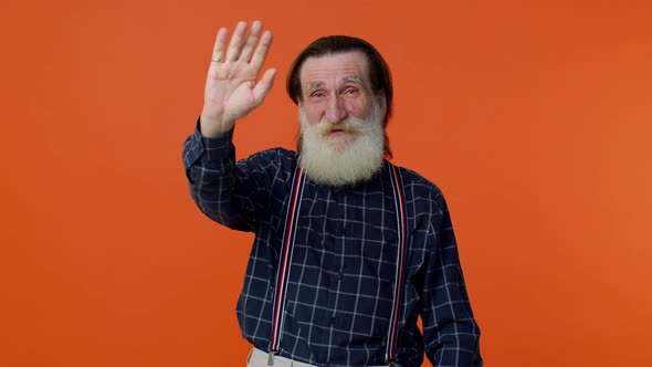 Happy Friendly Elderly Man Waves Hand Palm in Hello Gesture Welcomes Someone Positive Emotions
