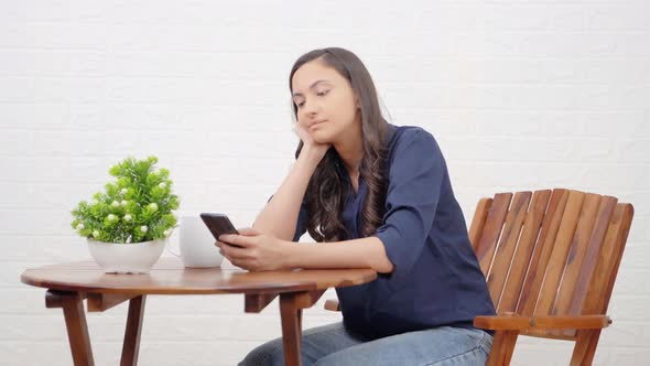 Indian girl scrolling phone at a cafe