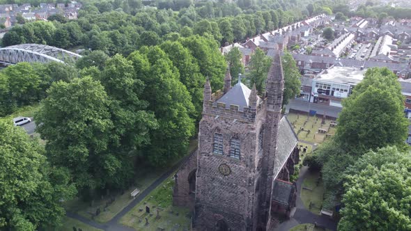 Aerial view above rural English town woodland countryside idyllic church bell tower and graveyard alt