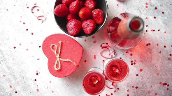 Bottle of Rose Champagne, Glasses with Fresh Strawberries and Heart Shaped Gift