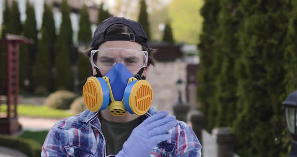Portrait of Virologist in Glasses and Respirator Shows Stopsign at Camera