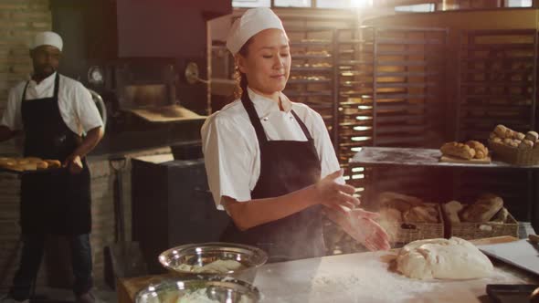 Animation of happy asian female baker clapping hands to clean flour