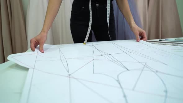 Creative dressmaker moving clothes pattern lying on table in fashion atelier