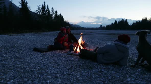 Group of friends sitting at a bonfire at dawn