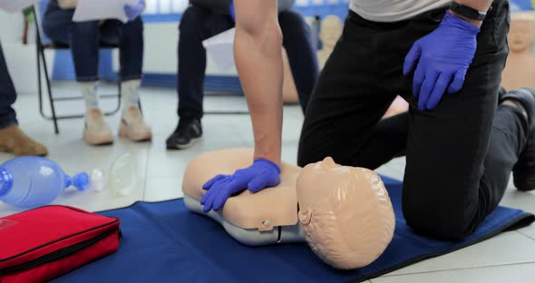 Close Up Man Demonstrating CPR on Teen Mannequin in First Aid Class