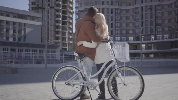 Portrait of a Young Happy Couple in Love Smiling and Communicating with the Bike Standing on the