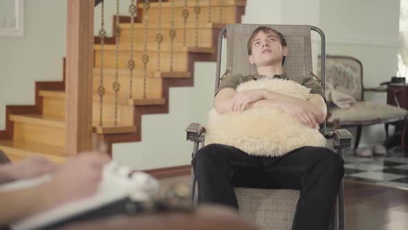 Relaxed Young Man Sitting in the Office of a Psychologist Telling Her About His Problems