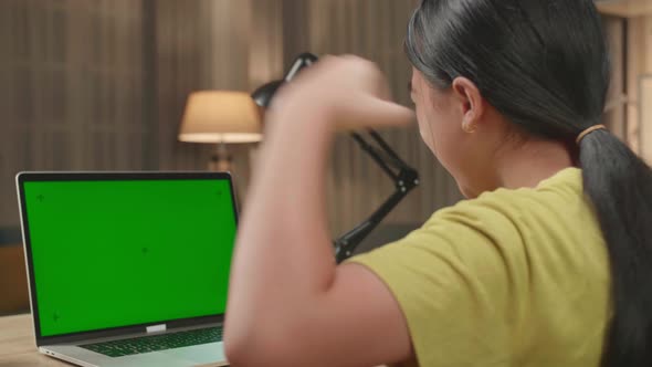 Asian Kid Girl Sitting In A Wheelchair While Using Laptop With Mock Up Green Screen And Celebrating