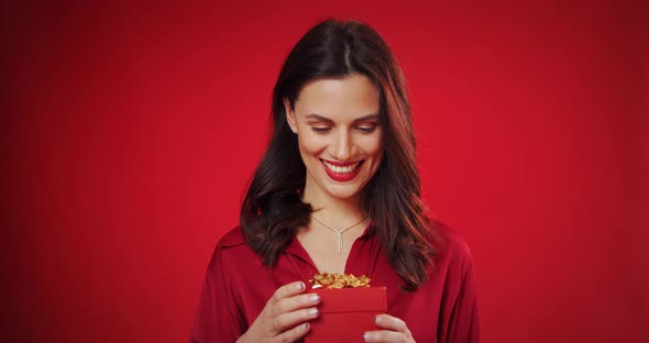 Beautiful Woman Enjoys a Valentine's Gift on a Red Background