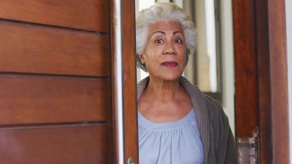 Portrait of african american senior woman opening front door and welcoming at home