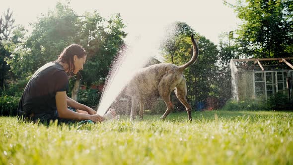 A Young Woman Freshens Up on a Hot Day By Dousing Herself and Her Dog with Water
