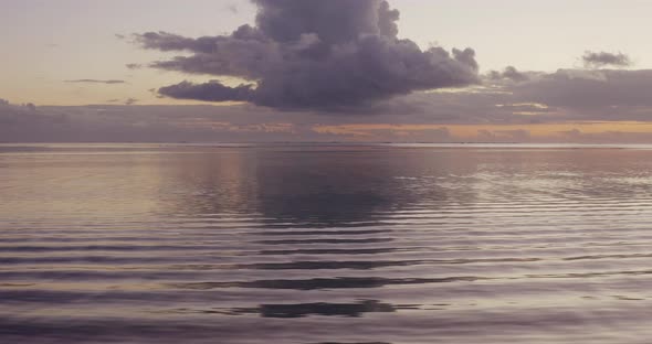 Flying over calm purple ocean at dusk