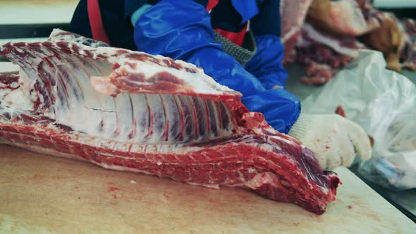 A Worker Cuts Meat at Meat Packing Plant.