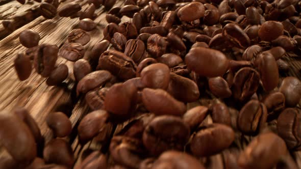 Super Slow Motion Detail Shot of Coffee Beans Strewing Towards on Wooden Background at 1000Fps