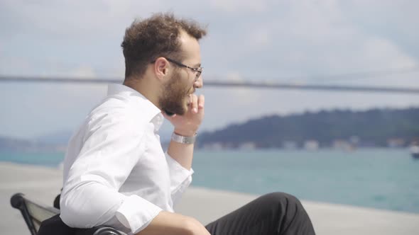 Businessman talking by phone by the sea.