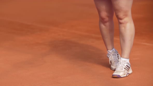 A Woman Hits a Tennis Ball on the Ground