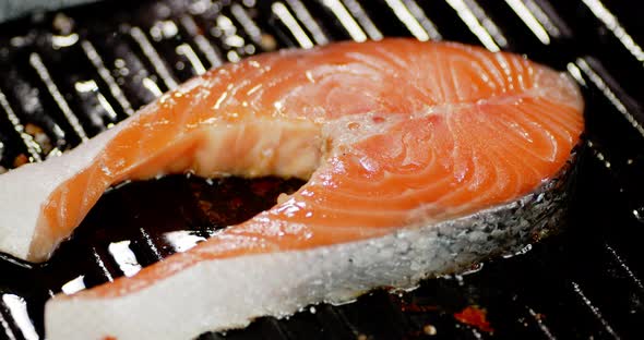 A Frying Pan with a Roasting Piece of Salmon Rotates. 