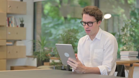 Young Man Making Video Call on Tablet in Modern Office