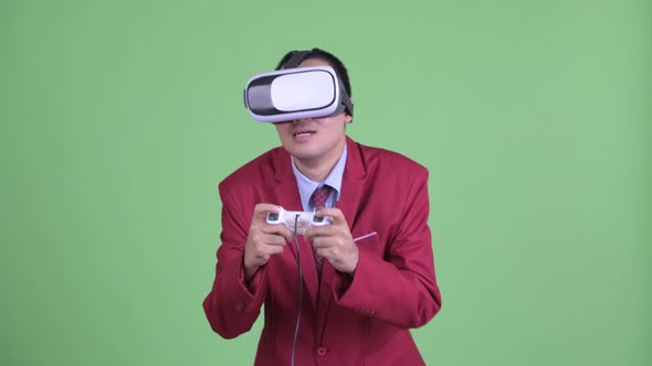 Asian Businessman in Suit Using Virtual Reality Headset and Playing Games