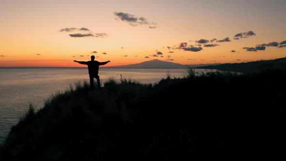 Silhouette of a boy raising his arms at sunset