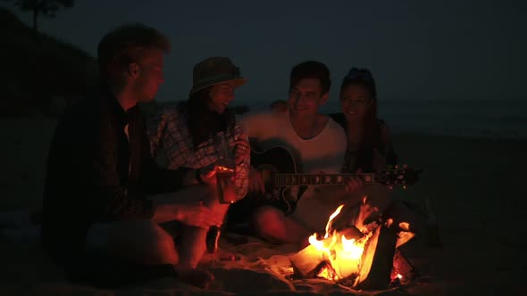 Picnic of Young People with Bonfire on the Beach in the Evening