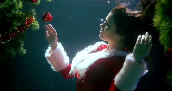 a Beautiful Long-haired Girl in a New Year's Red Suit, She Is Under Water, Smiling, Holding a Heart