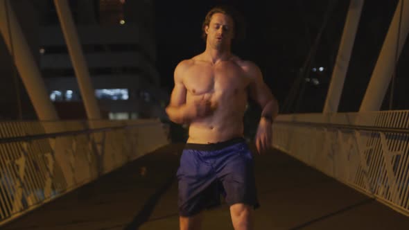 Caucasian shirtless male doing sport on a bridge in the evening