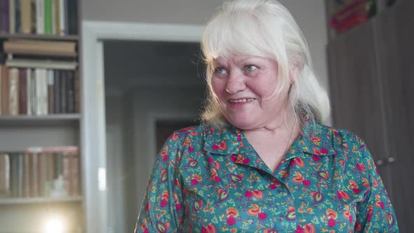 An Elderly Woman at Home Talking to Somebody and Smiling