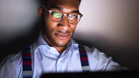 Young handsome black man at home at night using computer
