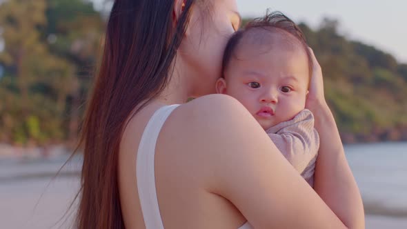 A young Asian mother is on the beach with her baby in summer time