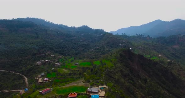 A colorful mountain shot with houses. Drone crossing mountain and houses and so much greenery.