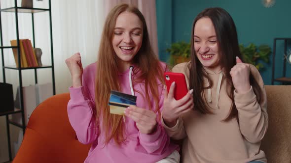 Cheerful Girls Friends Using Credit Bank Card and Smartphone While Transferring Money Purchases