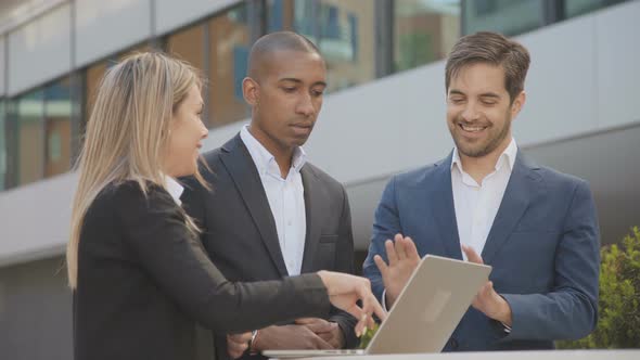 Coworkers Using Laptop and Talking Outdoor