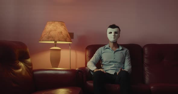 Anonymous man with mask sitting on the red sofa at home