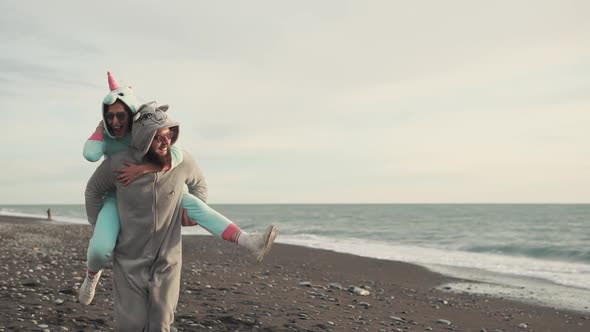 Happy Spouses in Kigurumi Costumes Running on a Stone Beach Near the Sea